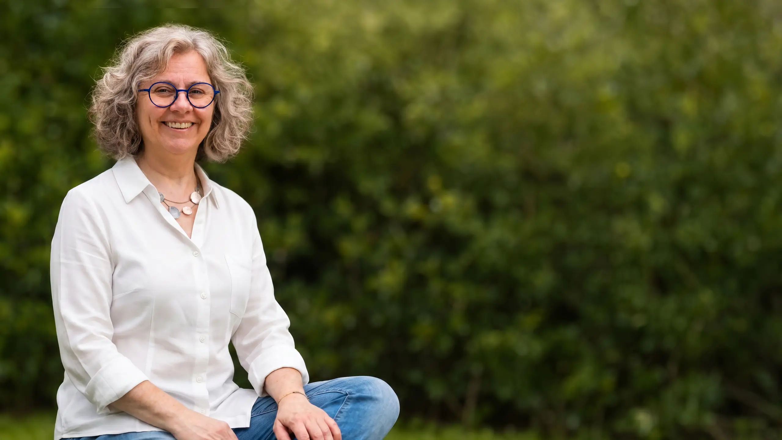 Alexandra Haider sitzt lachend im Grünen
